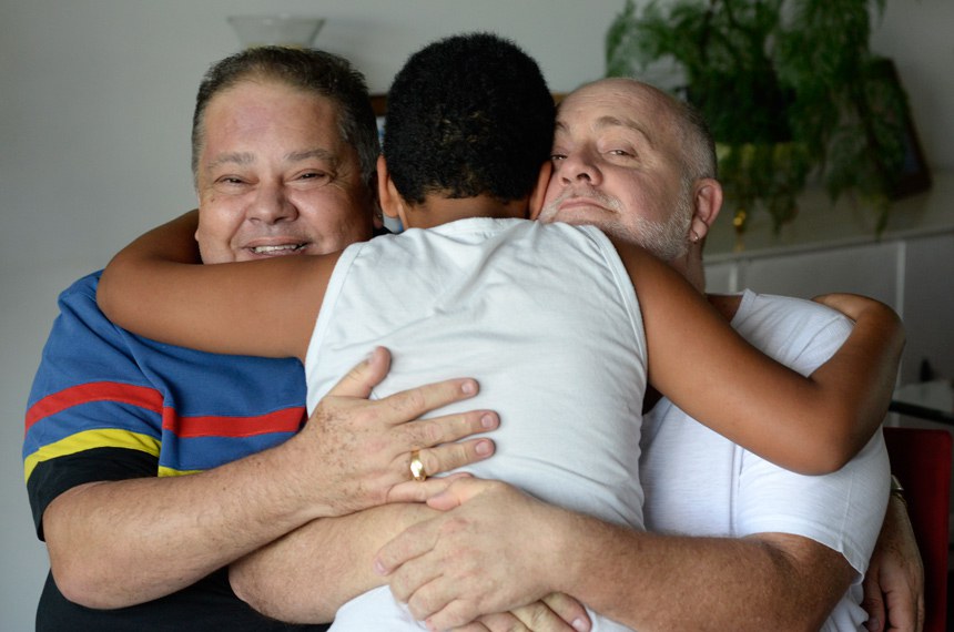 O casal Carlos Eduardo dos Santos e Osmir Júnior, de Brasília, com um dos quatro irmãos que eles adotaram há dois anos