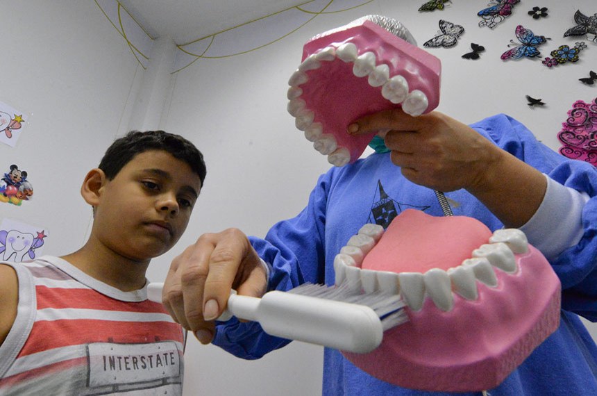 Dentista do SUS ensina paciente a escovar os dentes corretamente