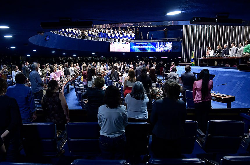 Plenário do Senado Federal durante sessão especial destinada a comemorar o Dia Internacional da Não-Violência Contra a Mulher. Em posição de respeito, parlamentares e convidados acompanham o Hino Nacional do Brasil executado pela banda do Centro de Ensino Fundamental nº 11. Mesa: representante do Ministério da Mulher, da Família e dos Direitos Humanos e coordenadora-geral do Programa Mulher Viver sem Violência, Valéria Laval; presidente e fundadora do Instituto Mulheres Feminicídio Não (AME), Lúcia Erineta; diretora-geral do Senado Federal, Ilana Trombka; presidente e requerente desta sessão de comemoração, senador Izalci Lucas (PSDB-DF); presidente nacional do Conselho de Mulheres Cristãs do Brasil (CMCB), Patrícia Óliver; juiz e coordenador do Núcleo Permanente Judiciário de Solução de Conflitos e Cidadania da Mulher em Situação de Violência Doméstica e Familiar do Distrito Federal do Tribunal de Justiça do Distrito Federal e Territórios (NJM/TJDFT), Ben-Hur Viza; delegada-chefe da 6ª Unidade Policial do Paranoá, Jane Klébia. Foto: Waldemir Barreto/Agência Senado