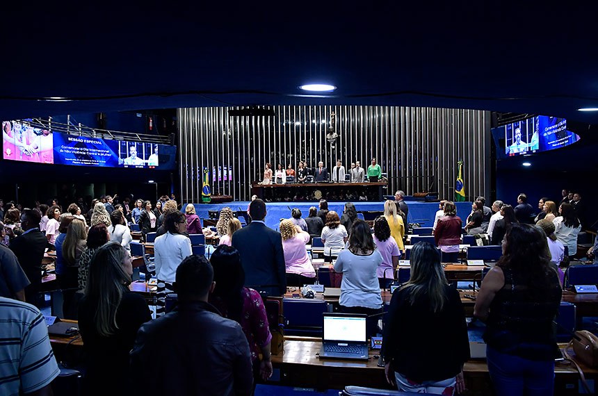 Plenário do Senado Federal durante sessão especial destinada a comemorar o Dia Internacional da Não-Violência Contra a Mulher. Em posição de respeito, parlamentares e convidados acompanham o Hino Nacional do Brasil executado pela banda do Centro de Ensino Fundamental nº 11. Mesa: representante do Ministério da Mulher, da Família e dos Direitos Humanos e coordenadora-geral do Programa Mulher Viver sem Violência, Valéria Laval; presidente e fundadora do Instituto Mulheres Feminicídio Não (AME), Lúcia Erineta; diretora-geral do Senado Federal, Ilana Trombka; presidente e requerente desta sessão de comemoração, senador Izalci Lucas (PSDB-DF); presidente nacional do Conselho de Mulheres Cristãs do Brasil (CMCB), Patrícia Óliver; juiz e coordenador do Núcleo Permanente Judiciário de Solução de Conflitos e Cidadania da Mulher em Situação de Violência Doméstica e Familiar do Distrito Federal do Tribunal de Justiça do Distrito Federal e Territórios (NJM/TJDFT), Ben-Hur Viza; delegada-chefe da 6ª Unidade Policial do Paranoá, Jane Klébia. Foto: Waldemir Barreto/Agência Senado