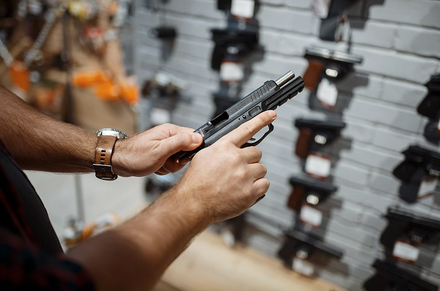Man Choosing New Handgun In Gun Shop  ------   Homem escolhendo nova arma de mao em loja, revolver. Venda de armas  Foto: Stockphotos