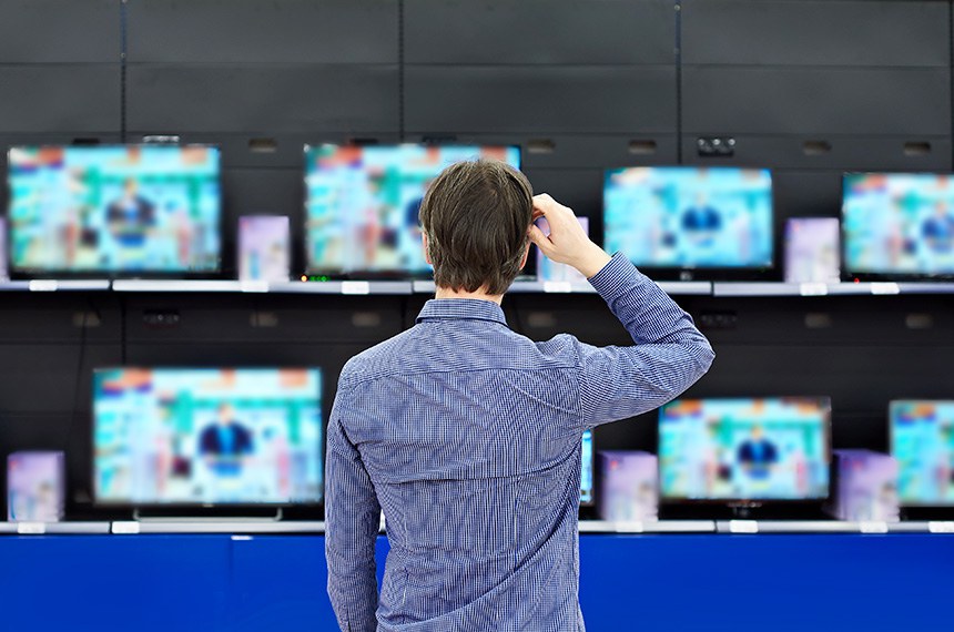 Homem observa aparelhos de televisão em loja de eletrodoméstico  Getty Images/iStockphoto