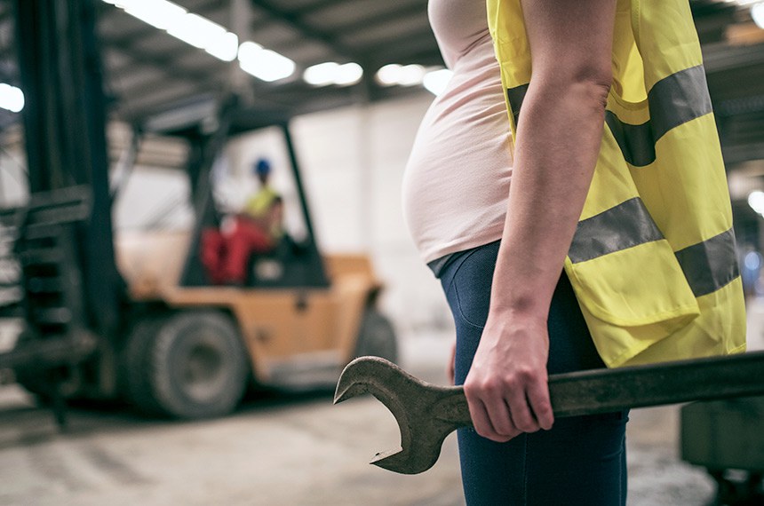 BIE - Mulher grávida que trabalha na fábrica de construção.  Pregnant woman working in construction factory. Man driving forklift in background  Foto: MaxRiesgo/iStockphoto