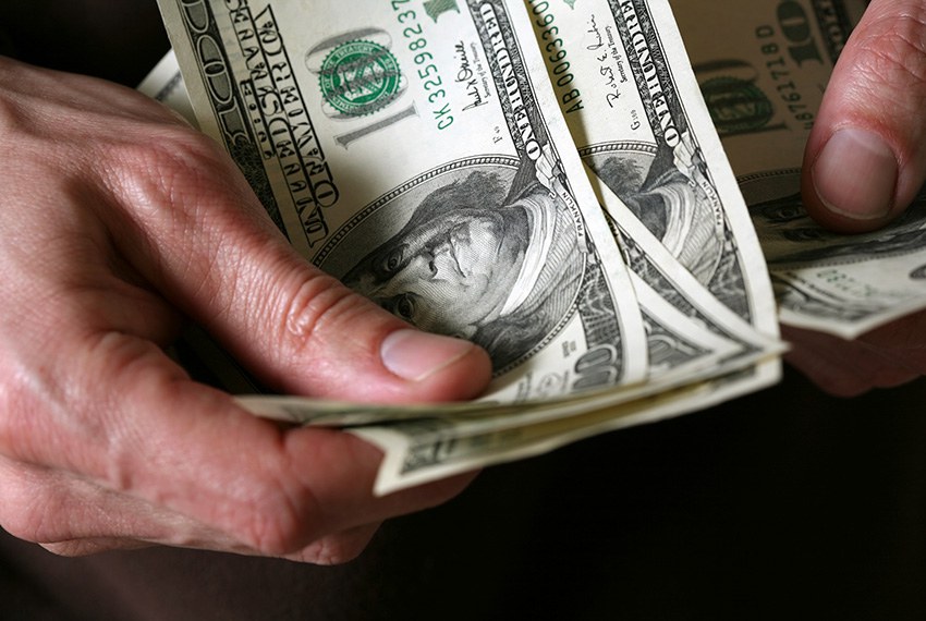 Homem segura notas de dolar  Getty Images/iStockphoto