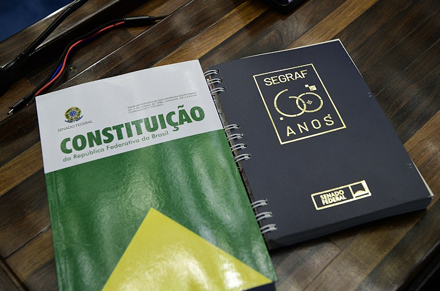 Sobre a mesa, Constituição da República Federativa do Brasil e encadernação com a capa dos 60 Anos da Segraf. 