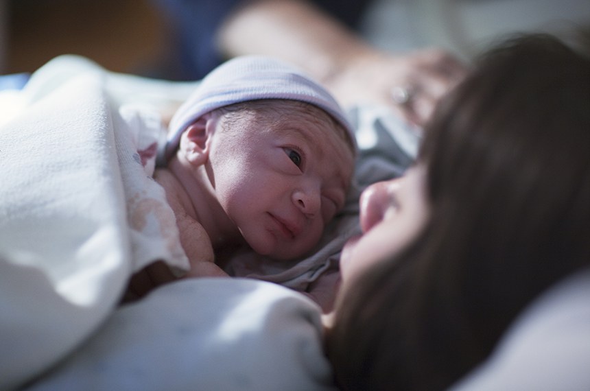 Um recém-nascido misturado raça caucasiano asiáticos no boné azul bebê descansar no peito morena mães asiáticas e olhares nos olhos pela primeira vez