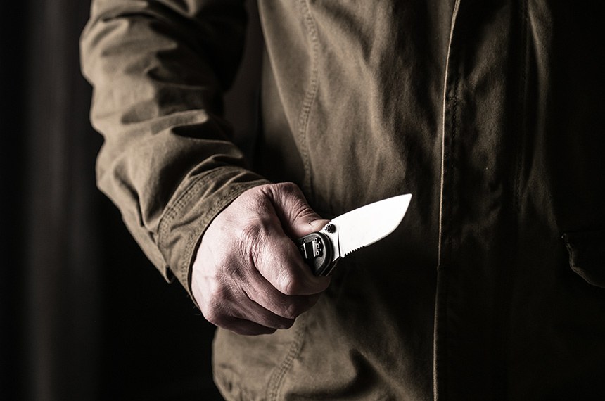 Homem segurando uma faca. Arma branca, violência, faca
