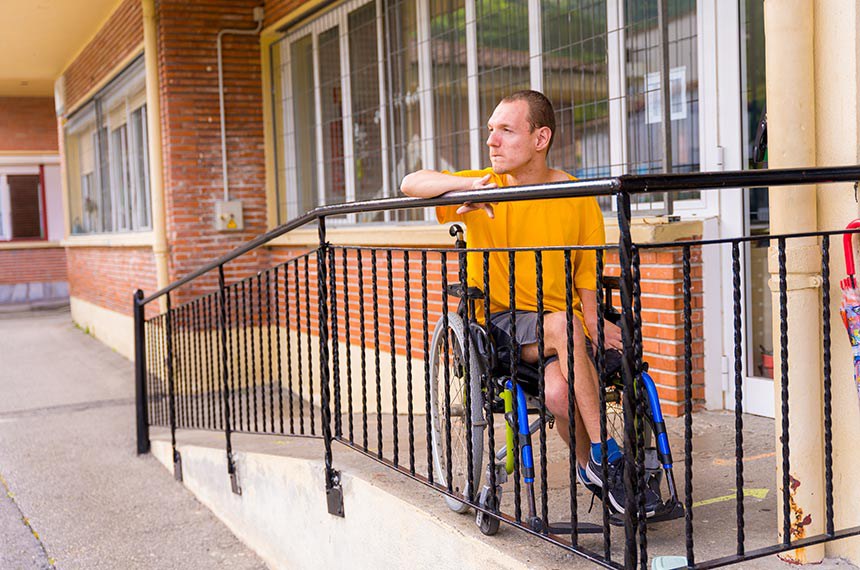 Cadeirante em rampa de acesso à porta de casa. Acessibilidade