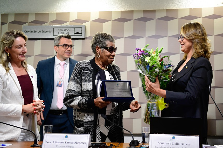 Participam à mesa:
assessora da ministra de Estado das Mulheres, representante de Ministério das Mulheres, Lucimara Cardoso;
homenageada Aída dos Santos Menezes;
filha da homenageada, Valeska dos Santos Menezes.