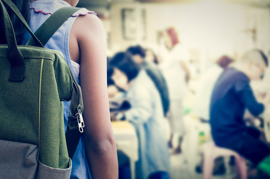 Garota de mochila entrando na sala de aula.