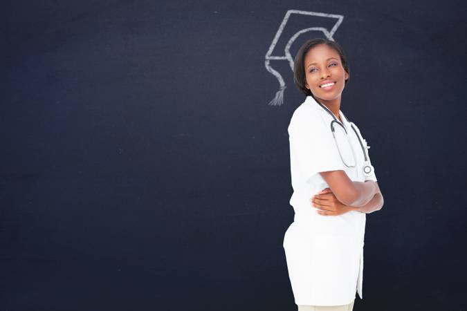 Young nurse with arms crossed against navy blue