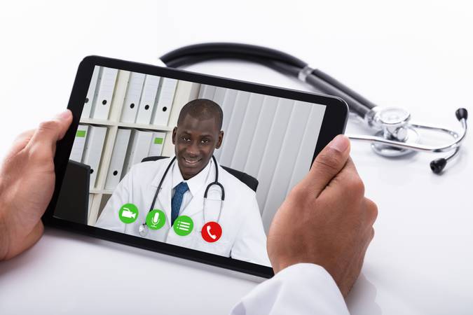 Close-up Of A Doctor's Hand Video Conferencing With African Male Colleague On Digital Tablet