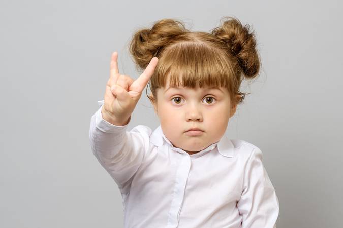 Portrait of little girl making rock and roll sign isolated