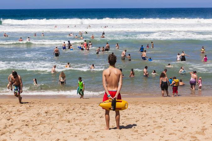 Ramsgate South Coast, South Africa - October 4, 2015: Lifeguard with safety rescue swimming buoy watching public swim in ocean waves