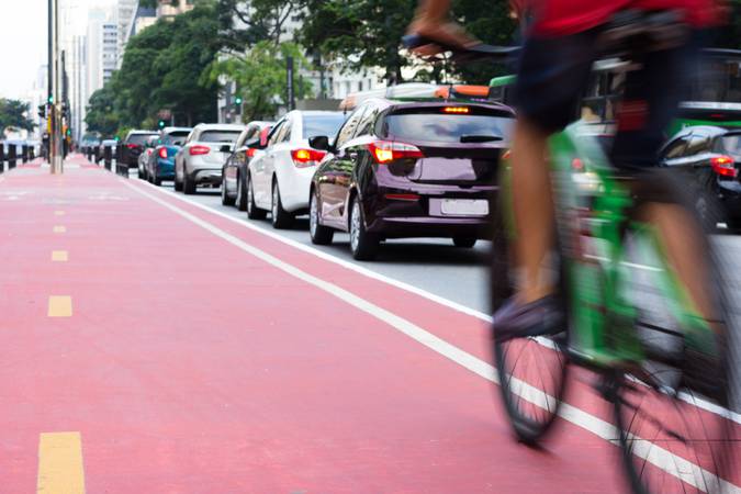 Cyclist passing bicycle lane and while a row of cars are stuck in traffic. Motion blur