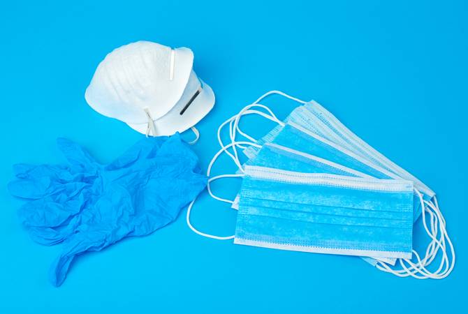 disposable gloves and stack of medical masks made of non-woven material with white rubber bands on a blue background