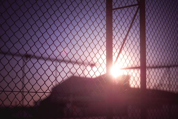 Sunset behind a rusty wire fence.