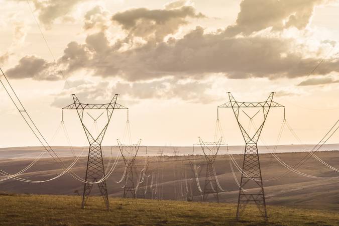 High voltage post. High-voltage transmission lines at sunset