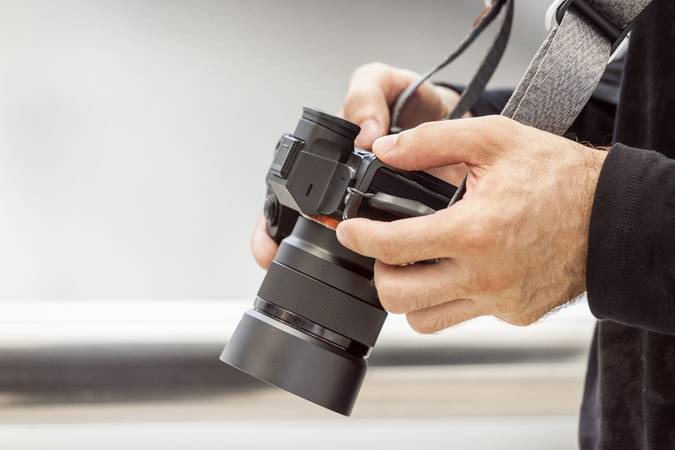 A professional photographer adjusts the camera before shooting, hands, camera, background