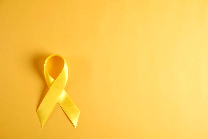 Yellow ribbon - bladder, liver and bone cancer awareness symbol. Support our troops concept. Isolated background, copy space, close up, top view, flat lay