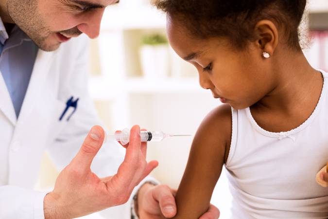 Doctor pediatrician injecting vaccine to cute african girl