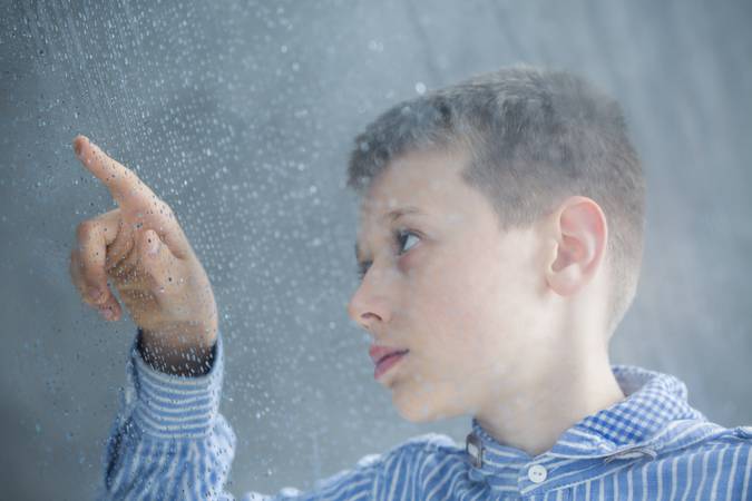 Photo through window of autistic child counting raindrops