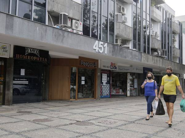 Imagem do comércio no Rio de Janeiro com algumas lojas fechadas e pessoas caminhando com máscaras.
