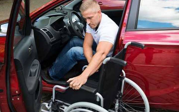 Motorista colocando a cadeira de rodas dentro do carro.