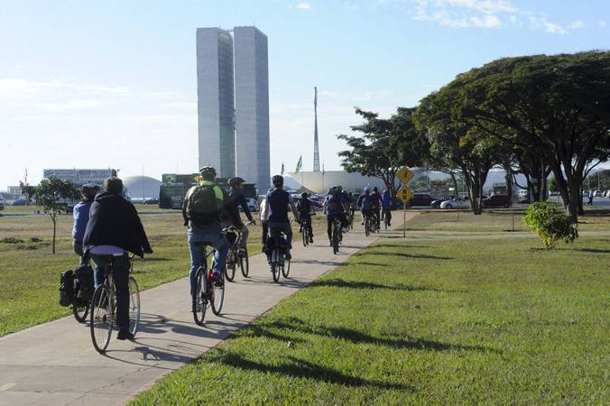 Pessoas indo para o Congresso Nacional de bicicleta. 