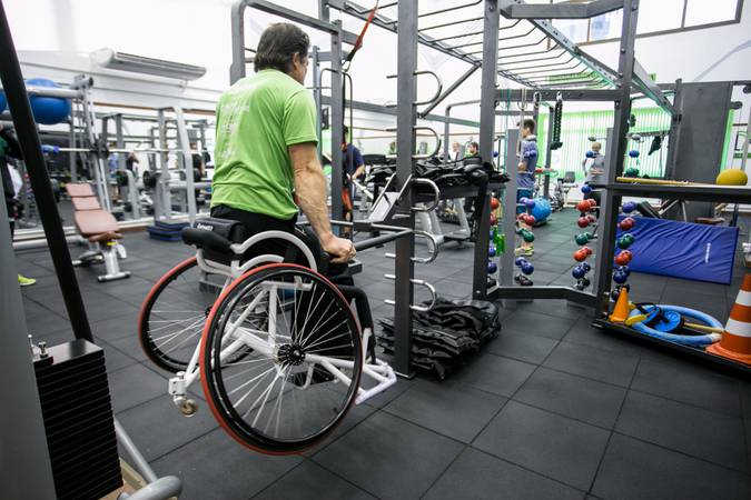 Pessoa com deficiência, usando cadeira de rodas, fazendo academia.