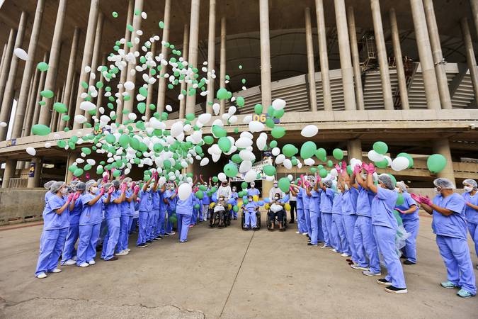 Profissionais de saúde comemorando alta de paciente na porta do Estádio Mané Garrincha, onde foi instalado hospital de campanha para atender pessoas com o novo coronavírus. 
