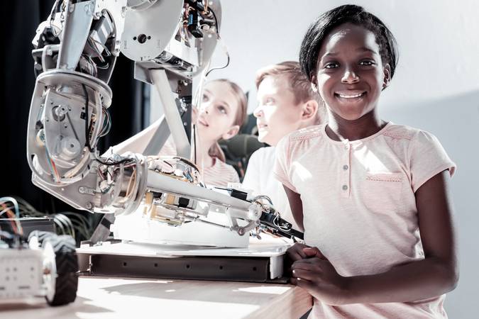 Getting smarter every day. Waist up shot of an African American girl looking into the camera with a cheerful smile on her face after visiting a work shop and seeing impressive robotic machines.
